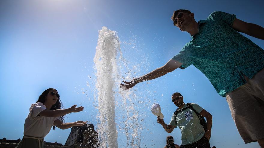 Algunas personas tratan de refrescarse en una fuente.