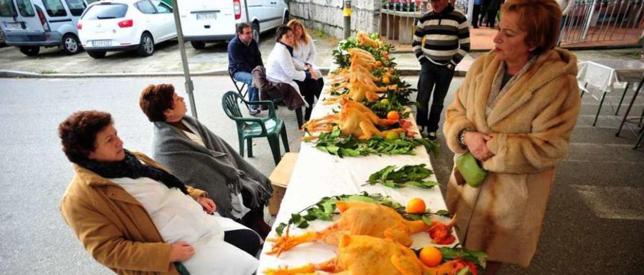 Productores y consumidores, frente a una mesa llena de gallos de corral, en Mosteiro. // Iñaki Abella