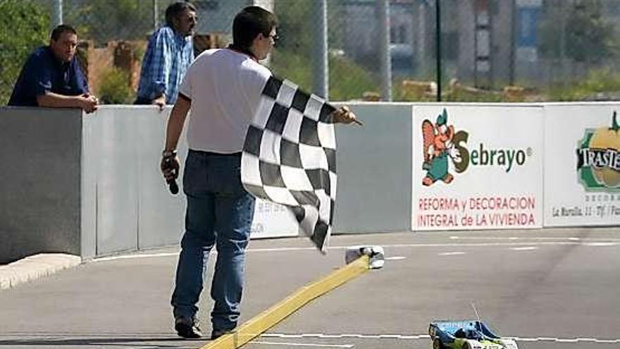 Un juez da el banderazo de llegada a uno de los coches.