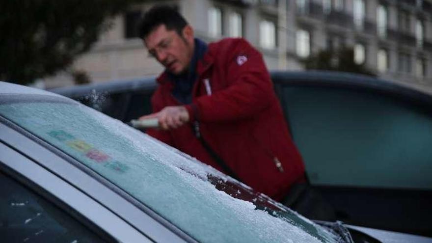 Un vecino de Lalín retira la escarcha del parabrisas de su automóvil. // Bernabé