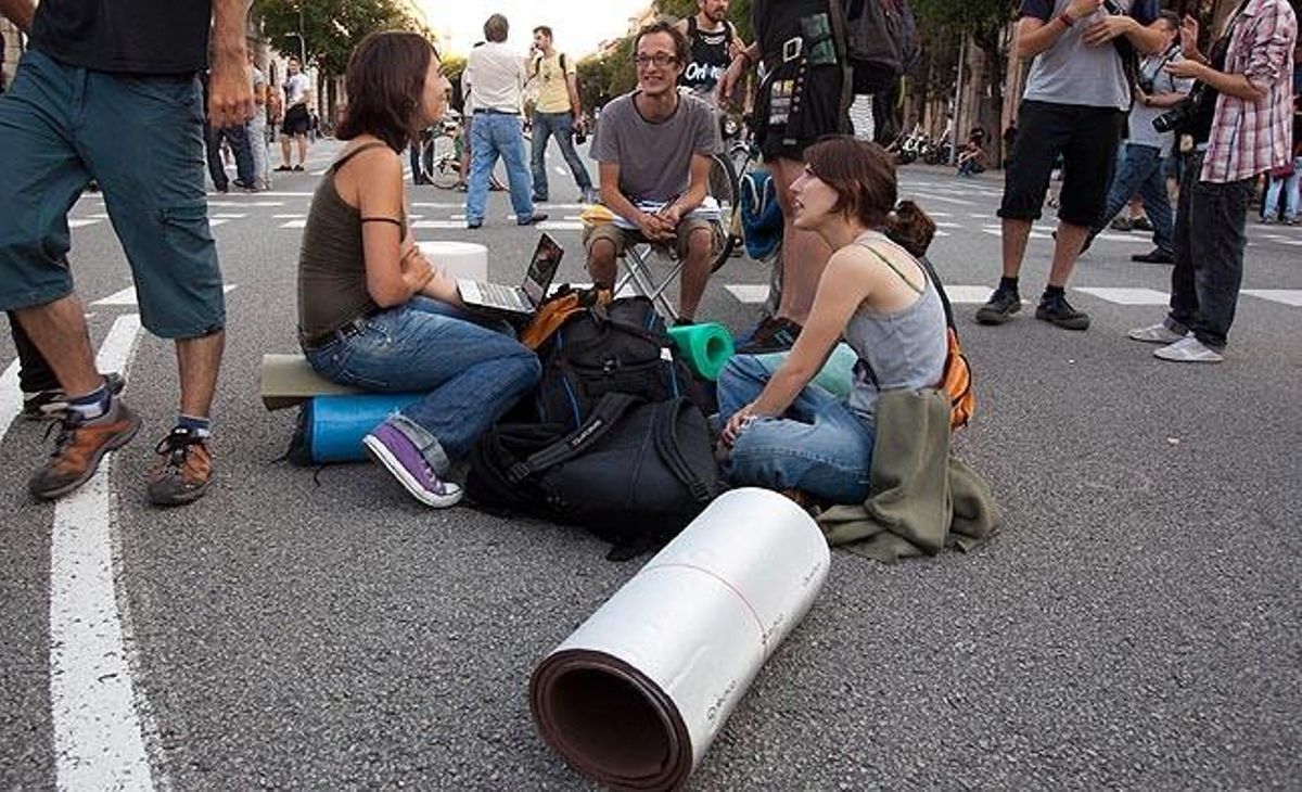 Uns nois amb estoretes i ordinadors parlen mentre es desenvolupen les protestes a la Ciutadella.