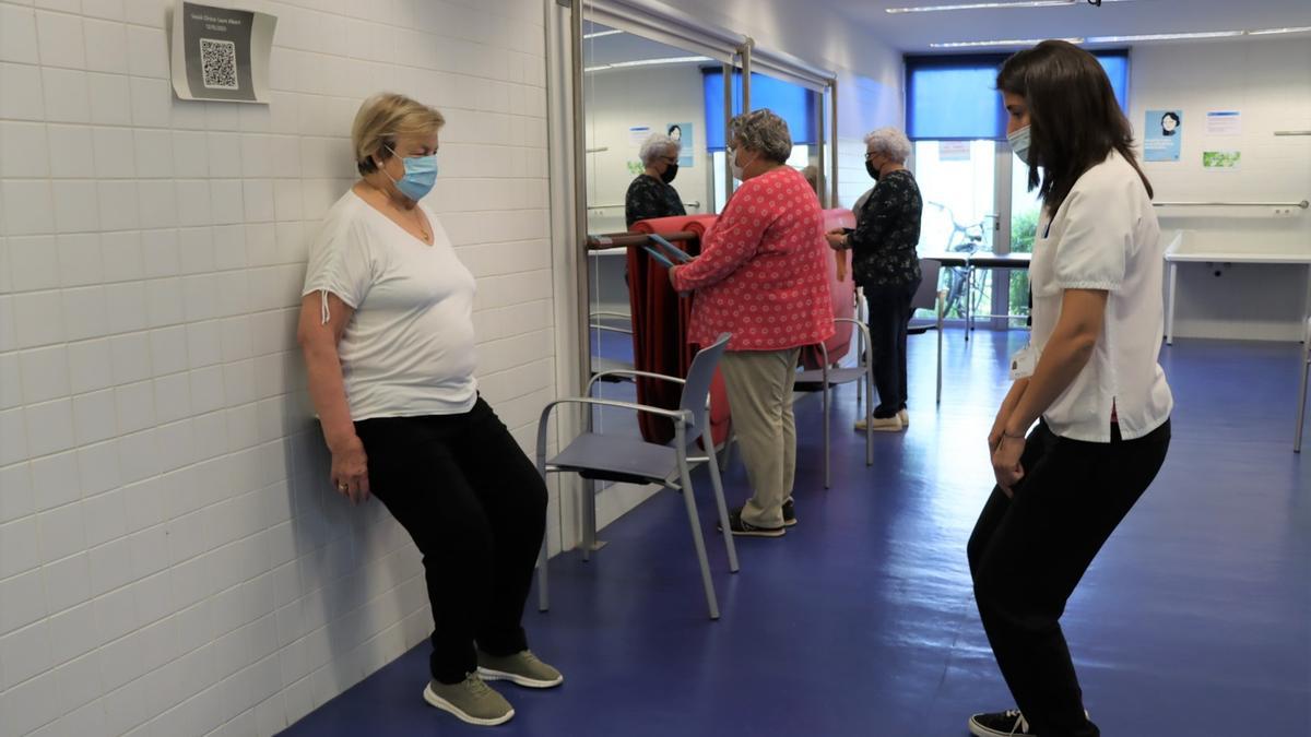 Una persona practica un dels exercicis amb una fisioterapeuta