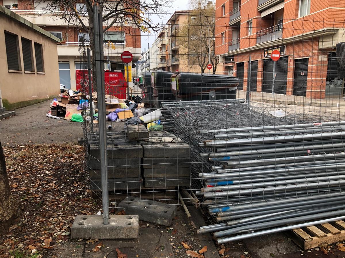 Tanques d'obra apilonades, deixalles acumulades i contenidors davant de l'església.