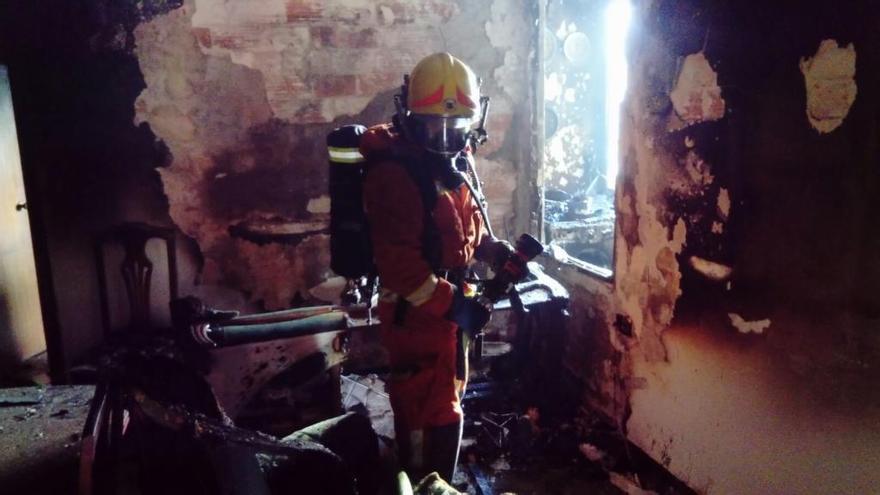 Un bombero inspecciona la vivienda calcinada.