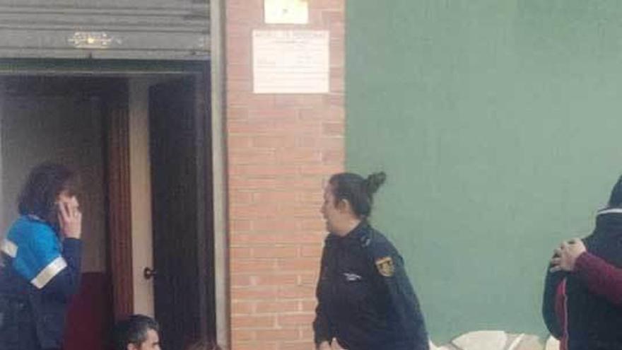 La mujer herida, en el suelo, es atendida por un policía local a la puerta de su pub, en Lugones.