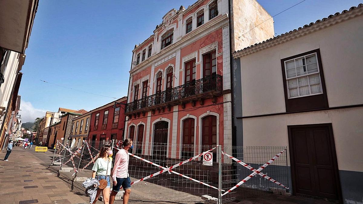 Una pareja pasa ayer frente a la casona del número 34 de la calle San Agustín, precintada tras sufrir desprendimientos en el interior.