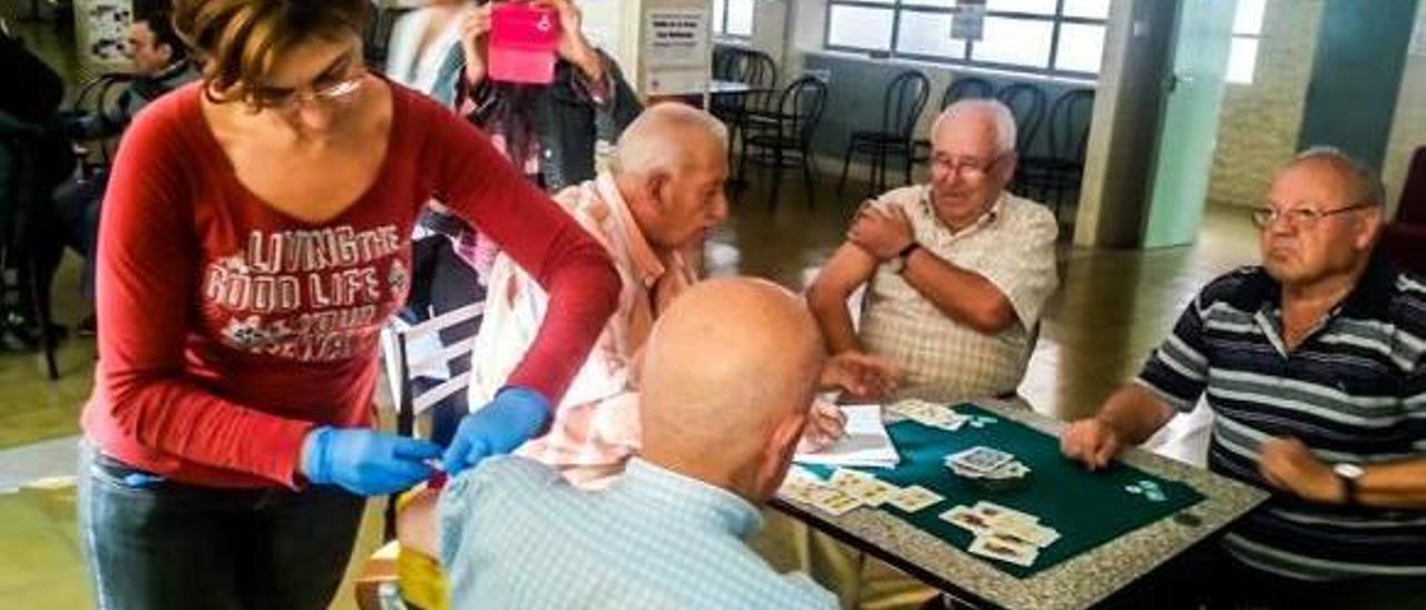 La edil de Sanidad suministrándole la vacuna a un grupo de mayores en plena partida de cartas.