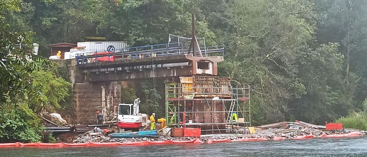 Obras en el puente de Quinzanas, ayer. A la derecha, piezas depositadas en la zona. | S. Arias