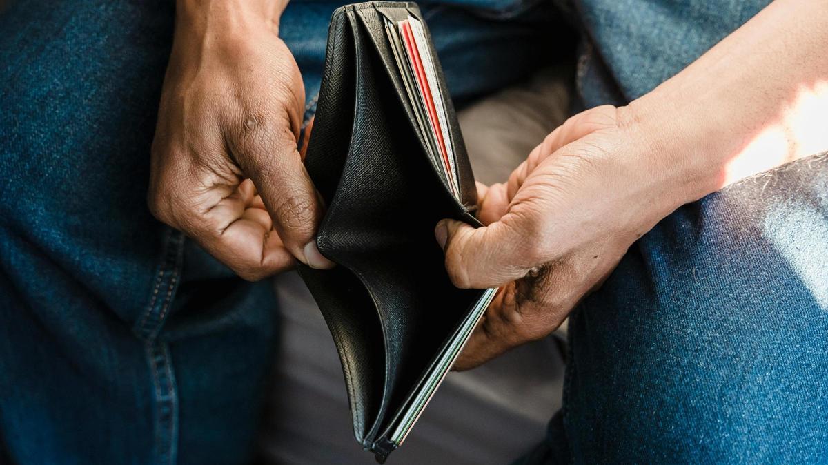 Hombre enseñando su cartera que está vacía.