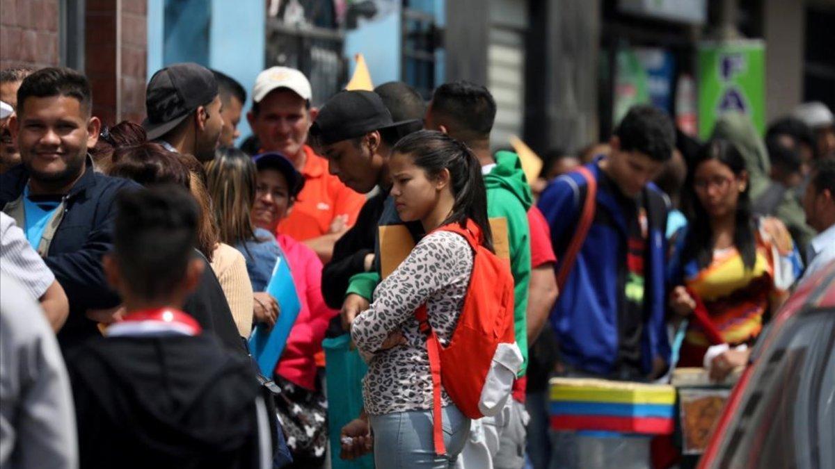 Migrantes venezolanos esperan en la cola de la oficina de inmigración en Lima