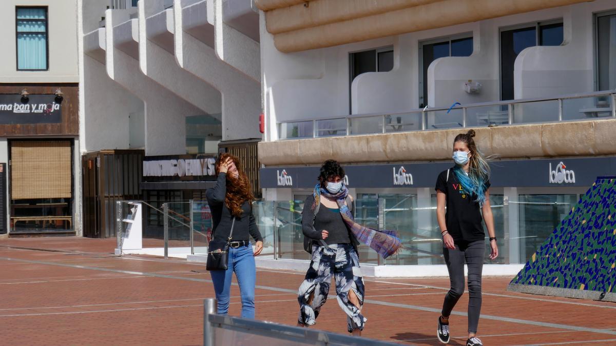 Tres jóvenes caminan por un paseo marítimo en Las Palmas de Gran Canaria.