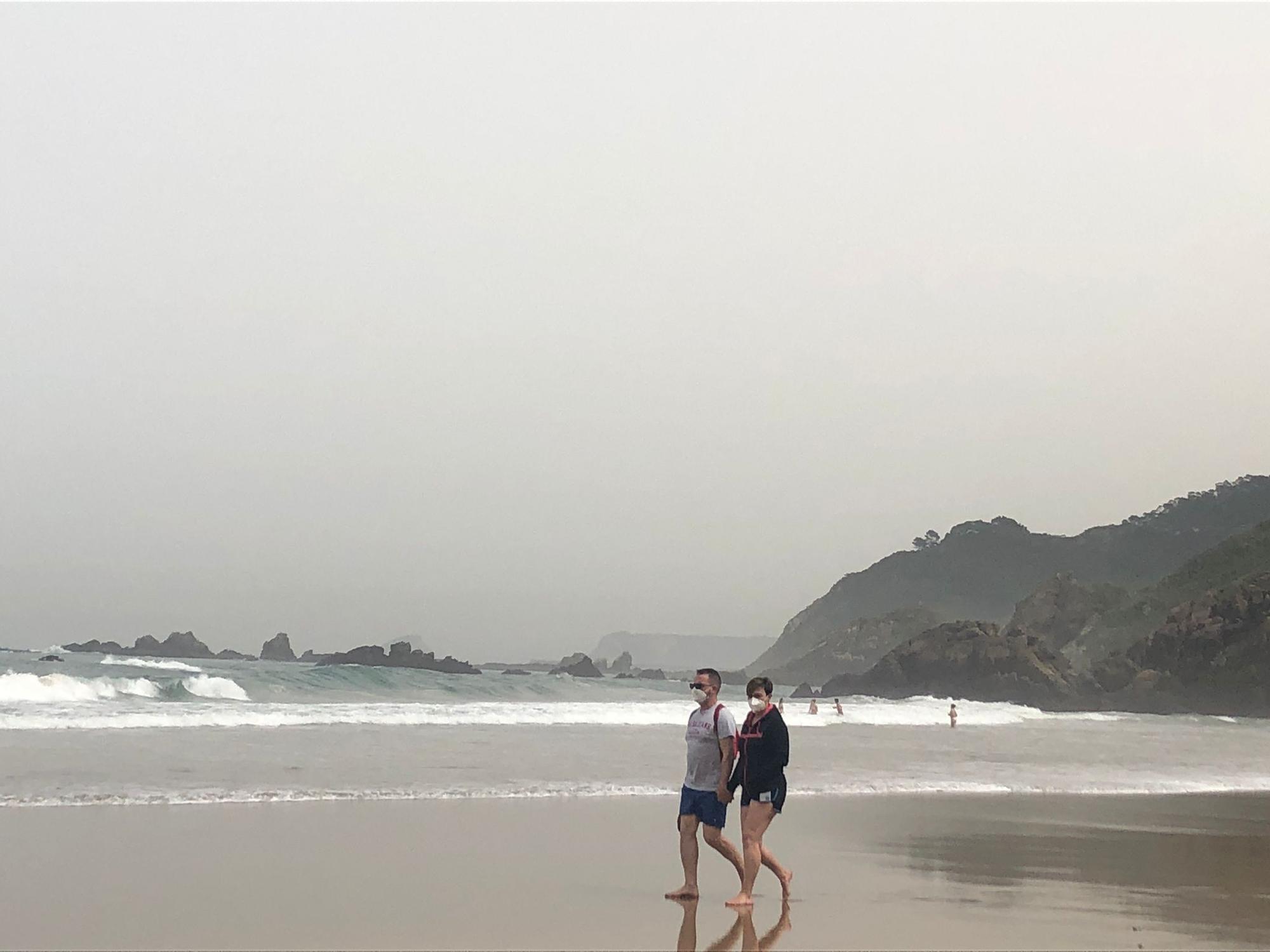 Paseantes por la playa de Aguilar, con mascarilla.