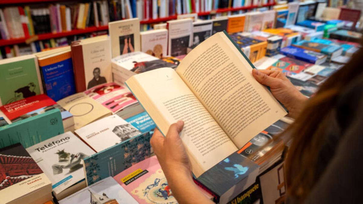 Persona amb un llibre obert en una llibreria