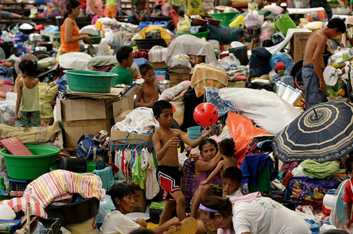 Diverses famílies que esperen a ser reallotjades omplen un gimnàs reconvertit en centre temporal d’evacuació a Manila (Filipines) després d’un brot de dengue.