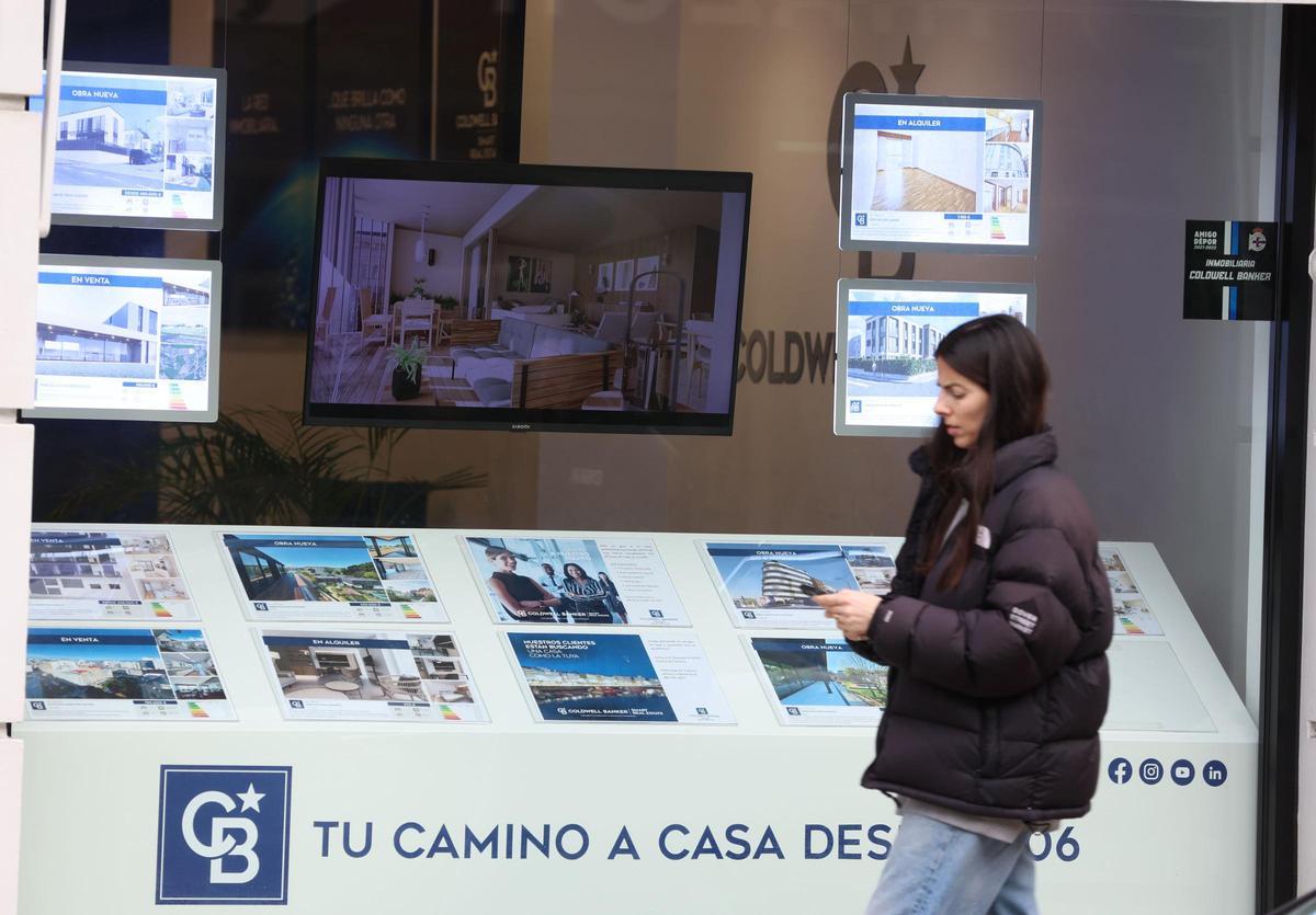 Una joven pasa por delante de una inmobiliaria en A Coruña