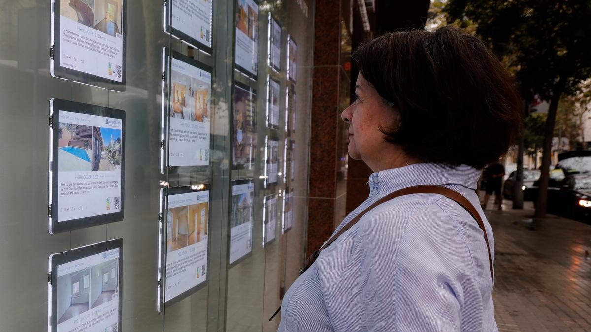 Una mujer mira anuncios de alquiler y venta de inmuebles en una inmobiliaria.