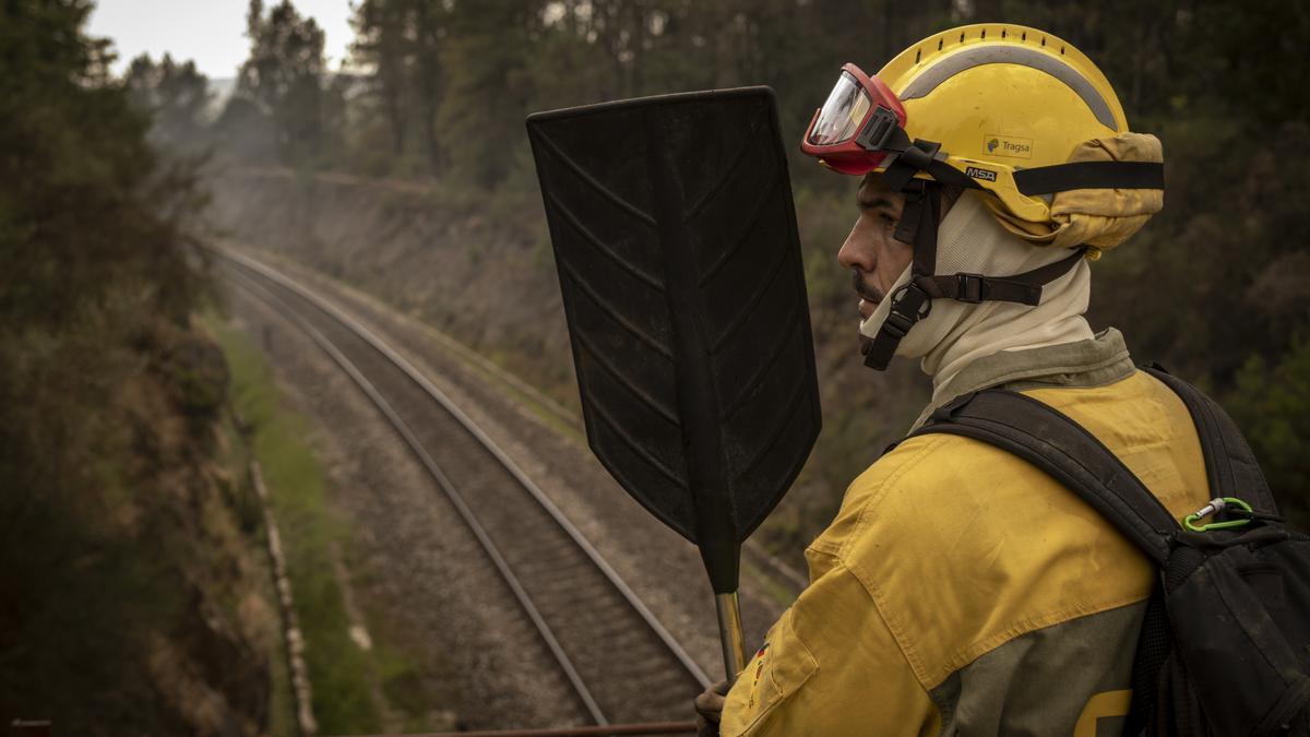 Un bombero forestal, atento al fuego cerca de la vía.