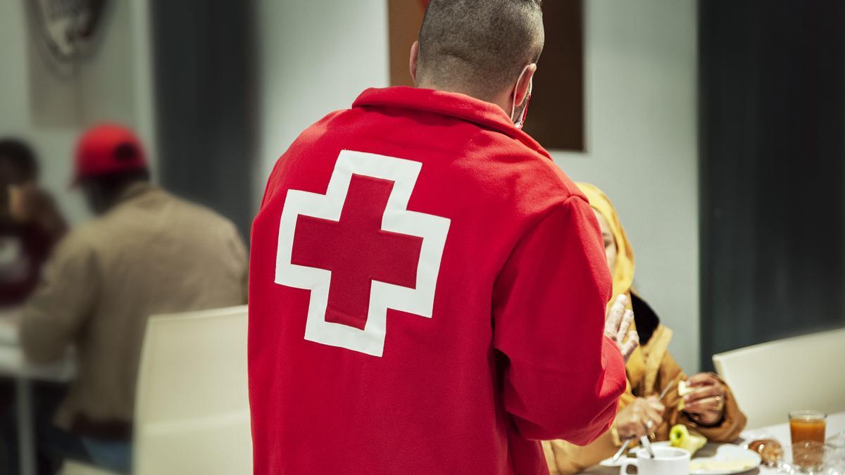 Un voluntario de Cruz Roja atiende a varias personas refugiadas.