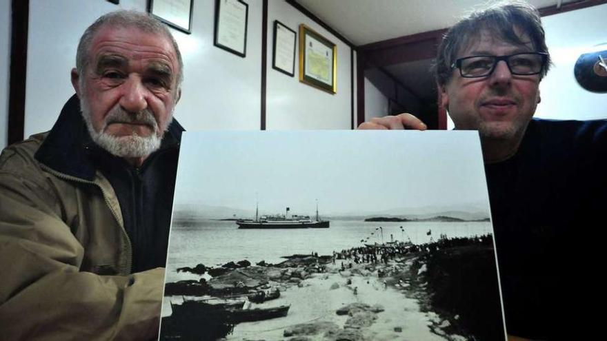 Teo Cardalda y Juan Carlos Porto muestran la fotografía del transatlántico alemán Cap Arcona, que estuvo durante cinco años fondeado frente a la costa de Vilaxoán. // Iñaki Abella