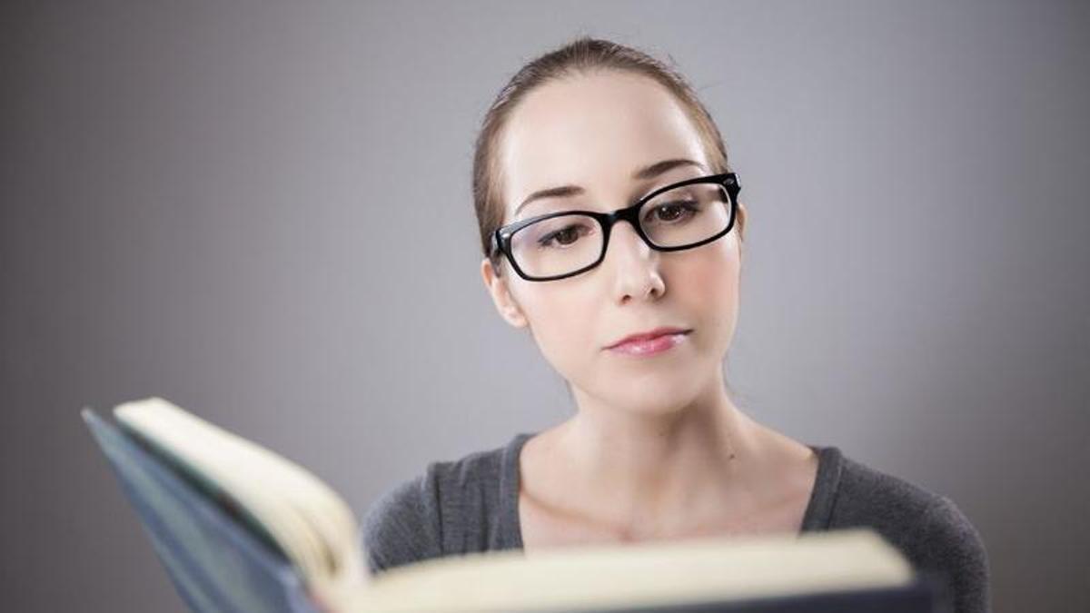 Imatge d'arxiu de dona amb ulleres llegint un llibre