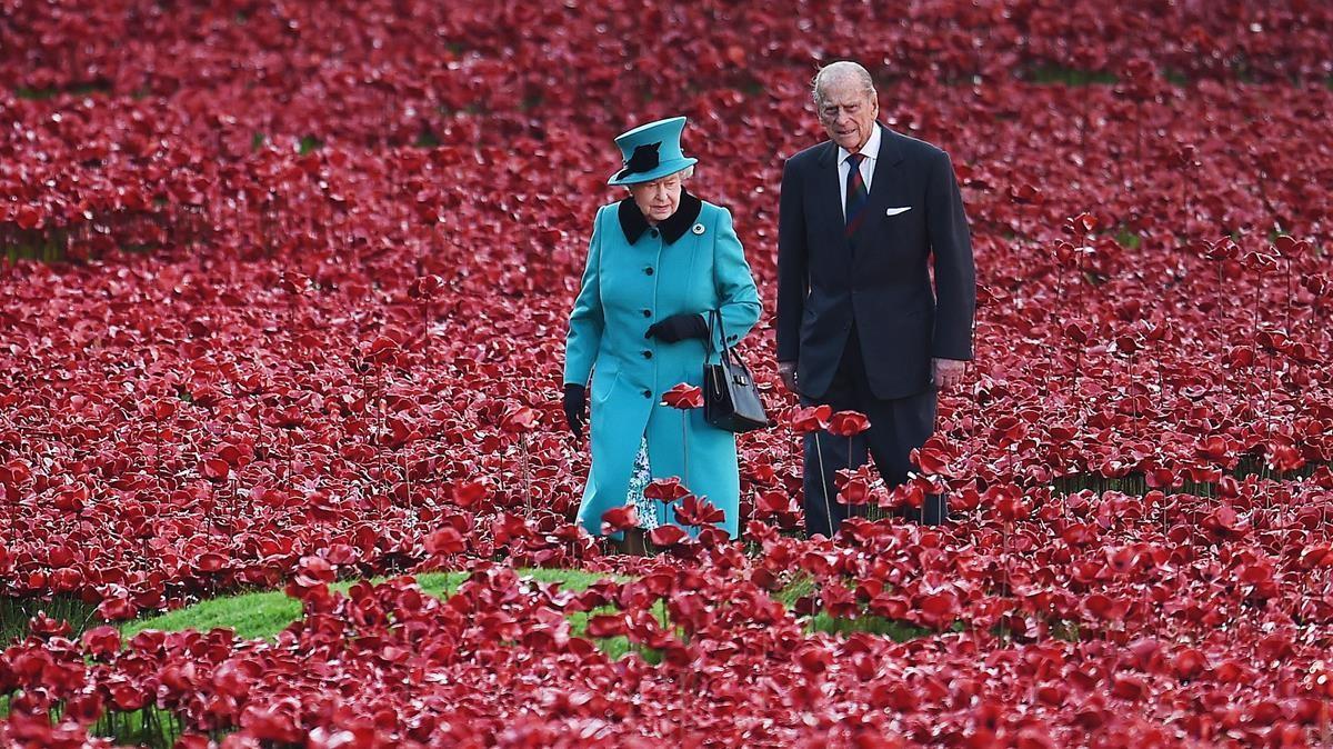 La Reina Isabel II y el Príncipe Felipe, Duque de Edimburgo caminando entre amapolas rojas de cerámica plantadas en memoria de los británicos muertos en la Primera Guerra Mundial en el foso de la Torre de Londres el 16 de octubre de 2014.