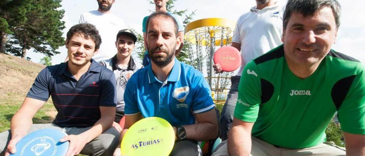 Miembros del Club Disc Golf Oviedo posan con sus discos ante una canasta.