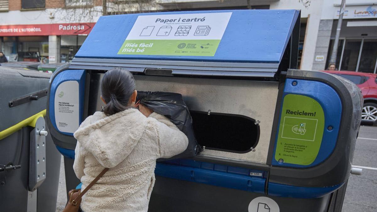 Una ciutadana gironina llança residus en un contenidor de paper i cartró, en una imatge d'arxiu.
