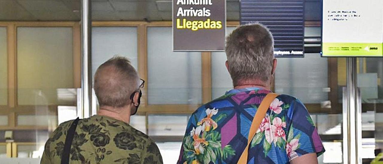 Dos turistas británicos miran el panel de salidas e el aeropuerto de Gran Canaria