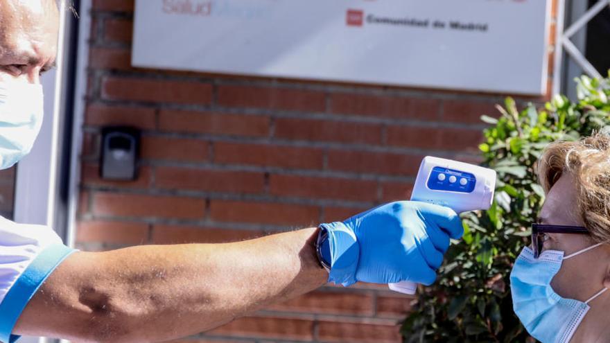 Una mujer se toma la temperatura ante un centro sanitario en Madrid.