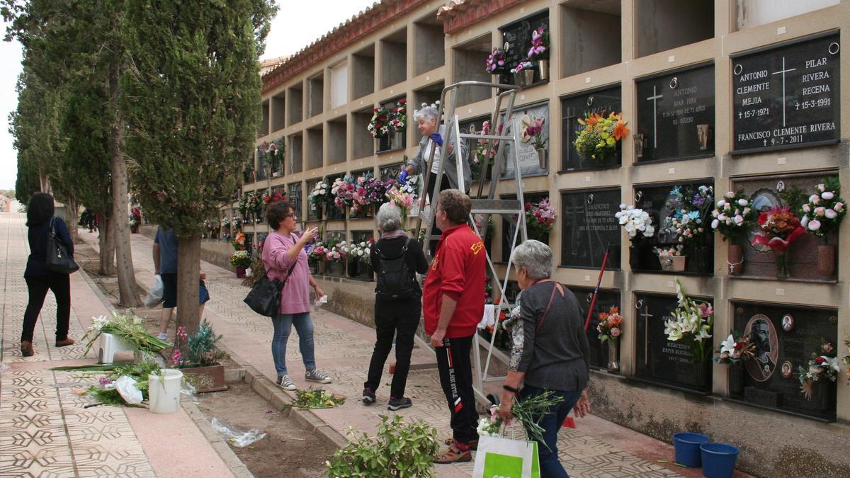 Lorquinos limpiando y poniendo flores en las tumbas de sus seres queridos.