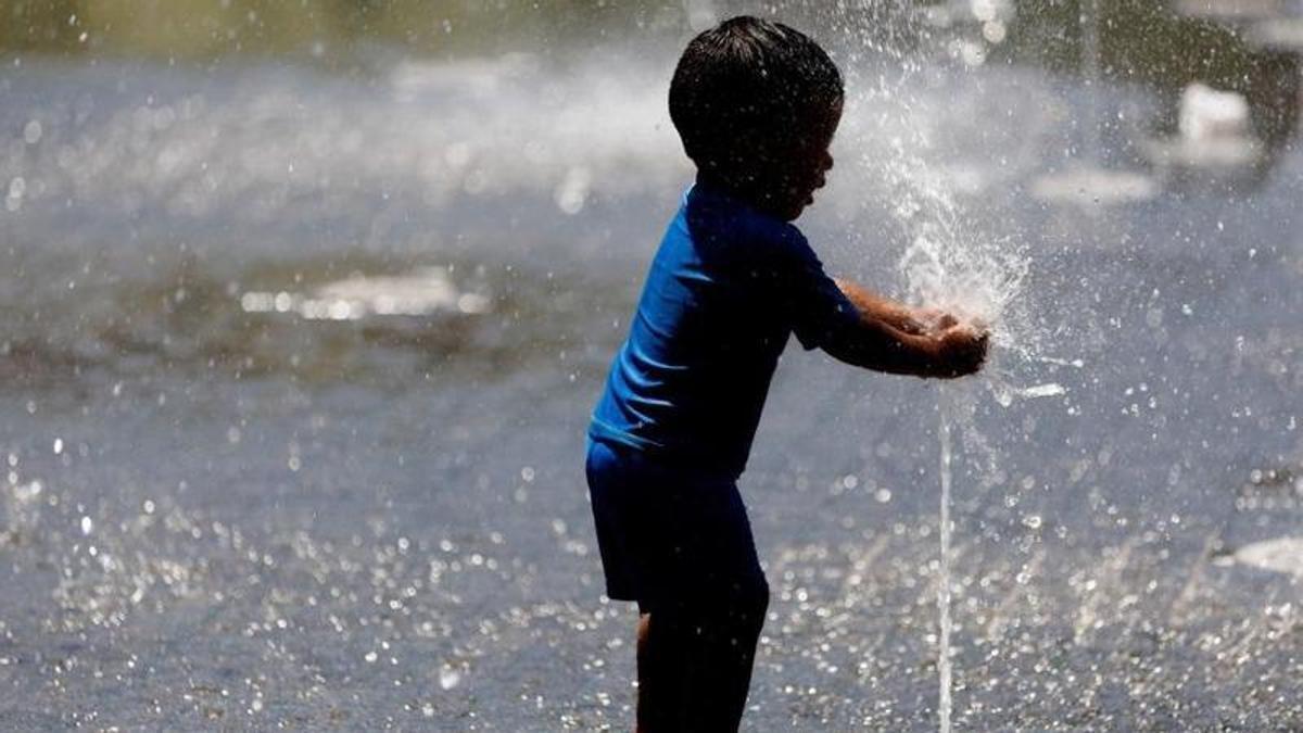 Un niño, refrescándose en una fuente.