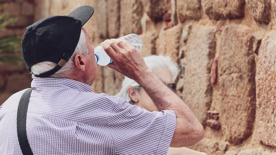 Un hombre con gorra bebe de una botella de agua.