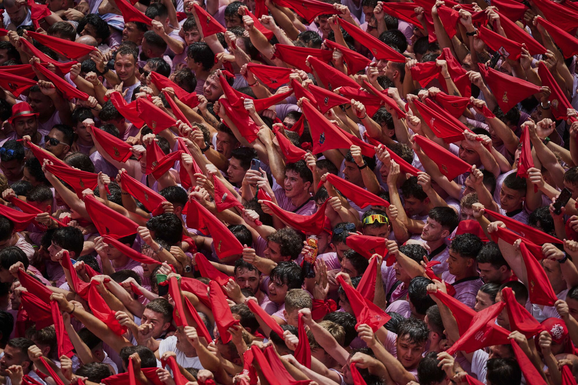 Revelers hold up red neckties as they pack the main square during the start of nine days of uninterrupted partying in Pamplona's famed running-of-the-bulls festival in Pamplona, Spain, Sunday, July 6, 2025. (AP Photo/Miguel Oses). EDITORIAL USE ONLY/ONLY ITALY AND SPAIN