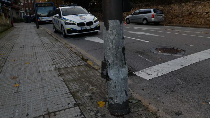 El primer término, el poste del semáforo contra el que chocó un coche con el abollamiento que delata el golpe; al fondo, el autobús urbano implicado en un accidente previo. | Mara Villamuza