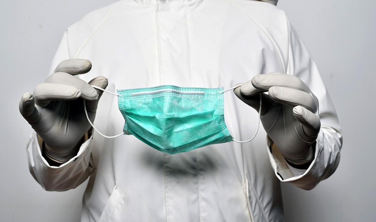 Un médico sostiene una mascarilla en sus manos