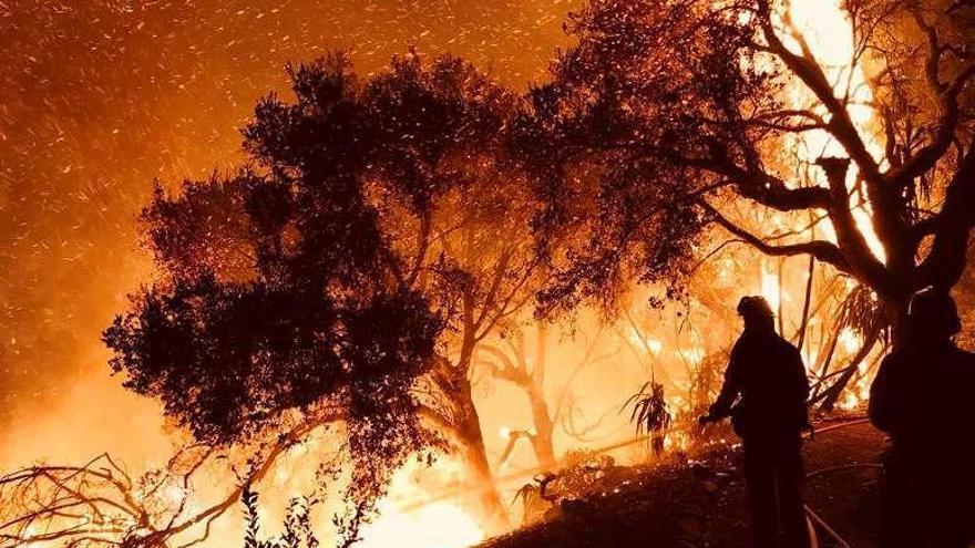 Los bomberos, en Carpinteria (California), junto a una carretera, tratando de apagar las llamas.