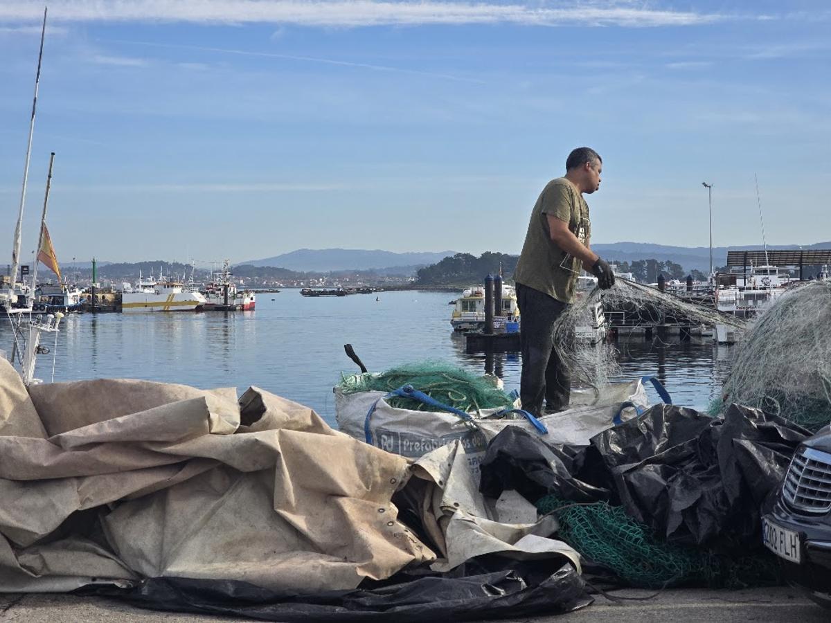 Un pescador sobre una montaña de miños en el puerto de O Corgo.