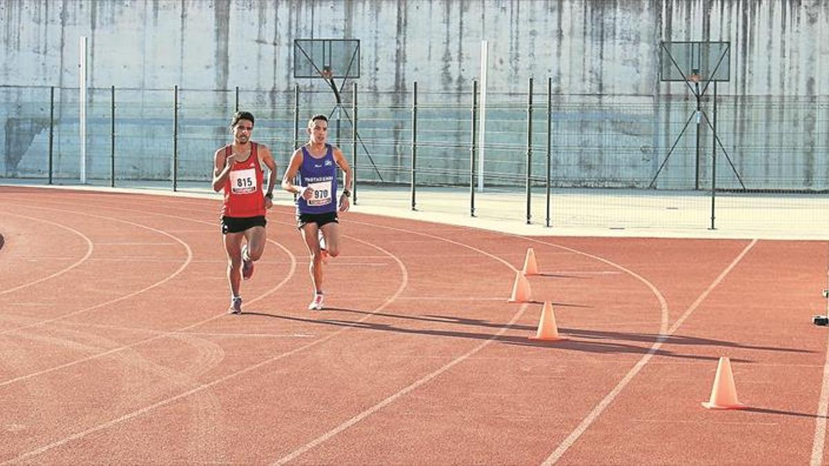 Dos personas entrenan en una pista de atletismo.