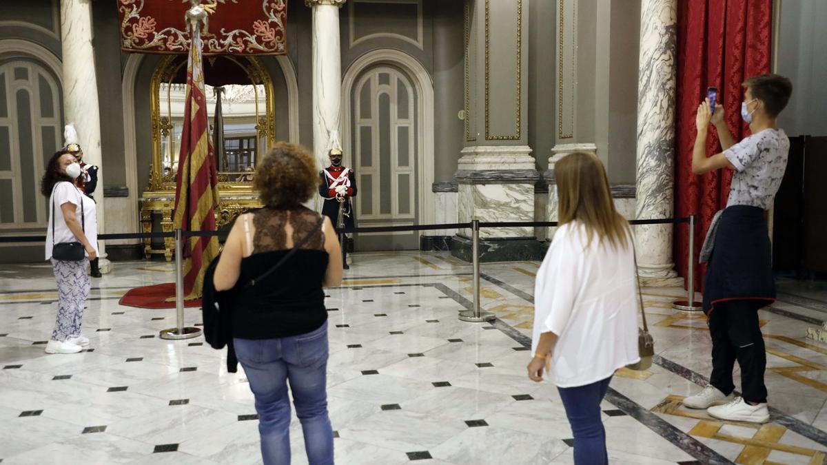 Un grupo de ciudadanos observa la Real Senyera en el Salón de Cristal.