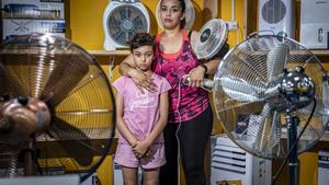 Hajar y su hija, Azahara, rodeadas de ventiladores en una tienda del Raval, en plena ola de calor.