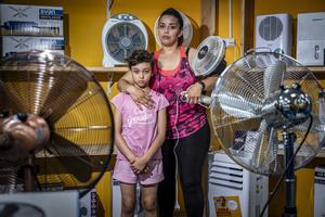 Hajar y su hija, Azahara, rodeadas de ventiladores en una tienda del Raval, en plena ola de calor.