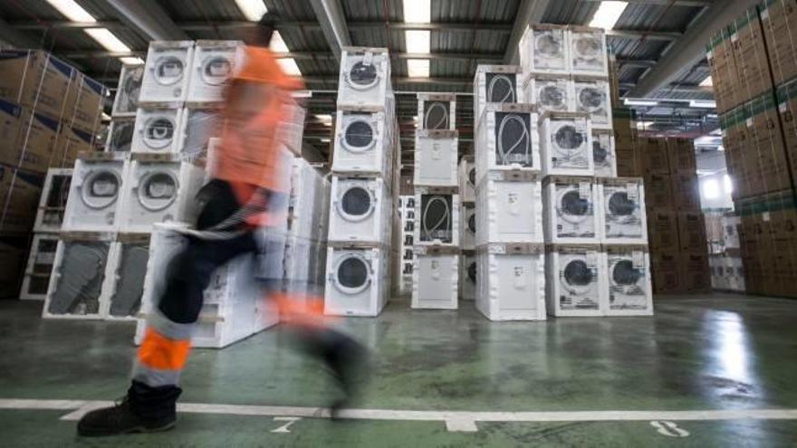 Un operario de un almacén pasa por delante de montones de lavadoras fuera de servicio.