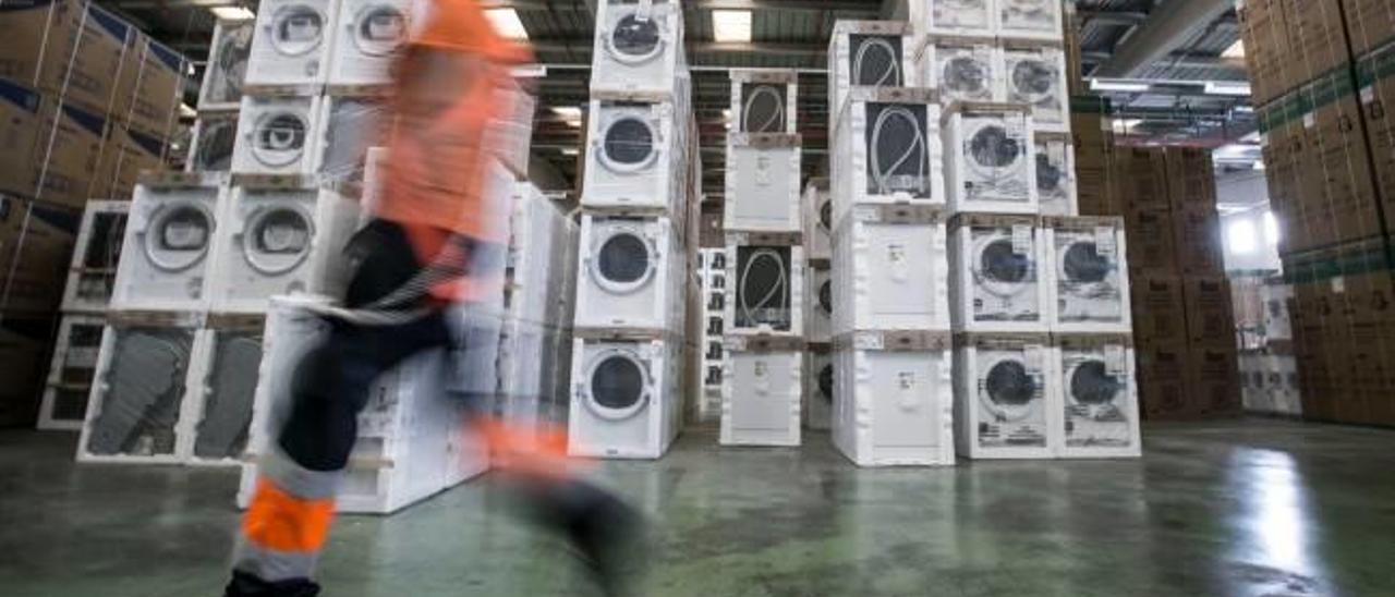 Un operario de un almacén pasa por delante de montones de lavadoras fuera de servicio.