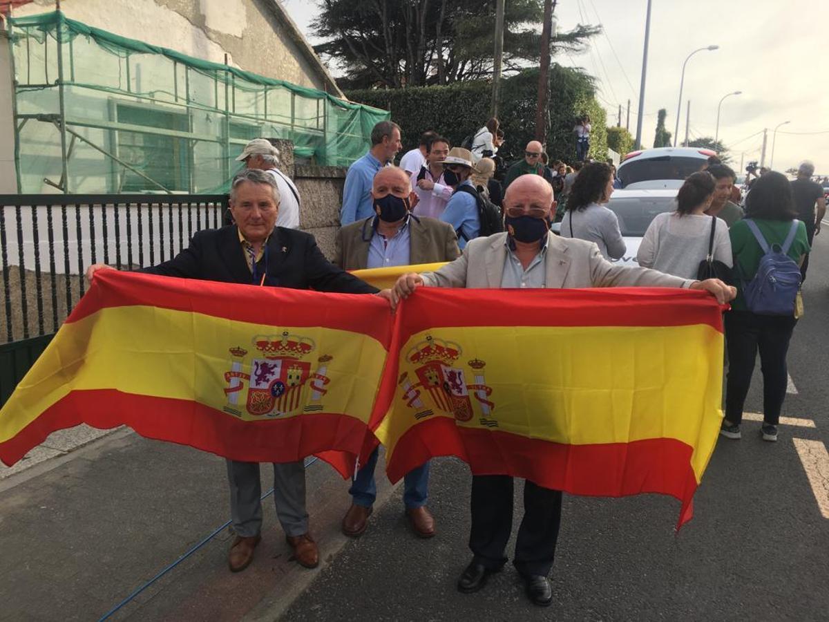 Tres hombres esperan a Juan Carlos I en Sanxenxo con banderas de España. Carlos García