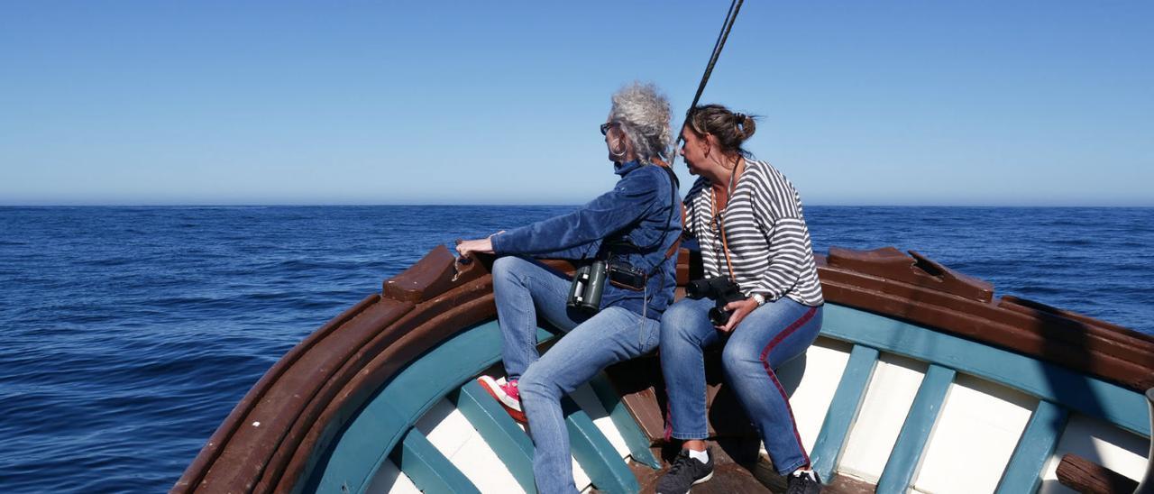 Dos mujeres observan aves en el “Corredor migratorio galaico-cantábrico occidental”,  a bordo del aula flotante de la naturaleza “Chasula”.