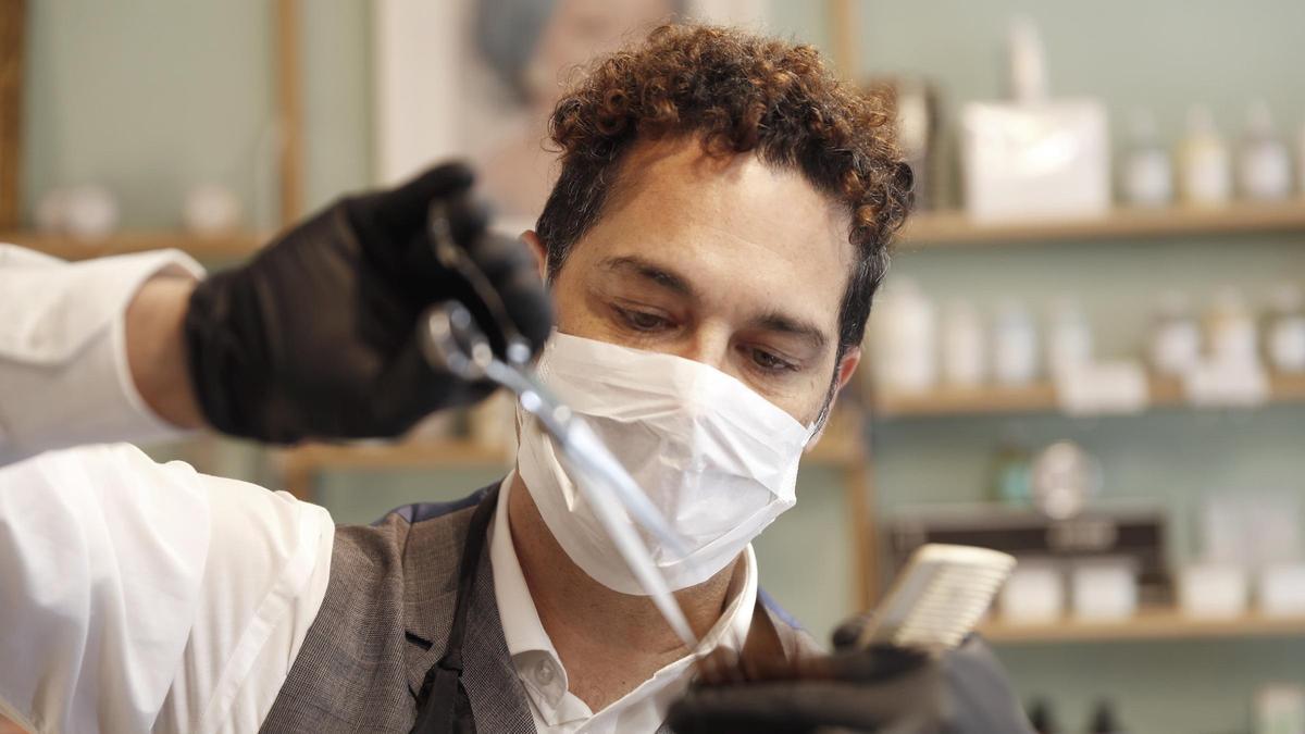 Un cliente se corta el pelo en una peluquería.