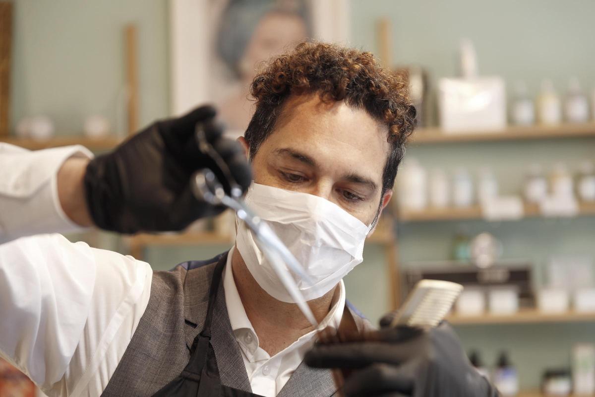 Un cliente se corta el pelo en una peluquería.