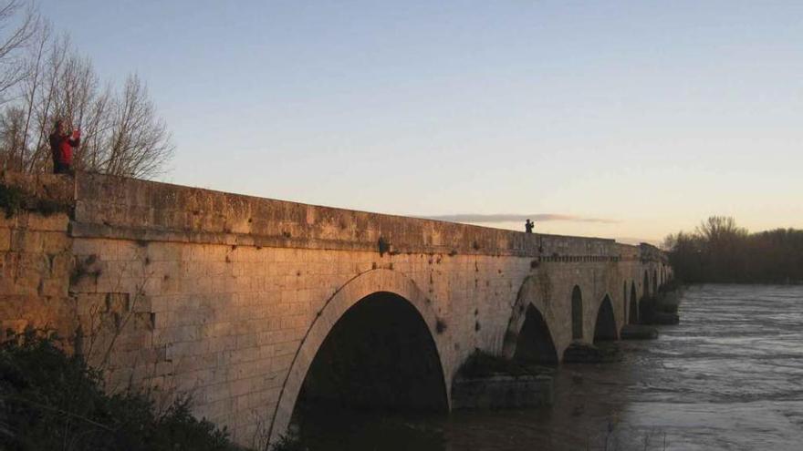 Vecinos toman fotografías del río Duero desde el puente de piedra de la ciudad. Foto