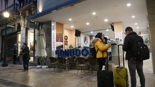 Una pareja con maletas a la puerta de un hotel avilesino. | Ricardo Solís