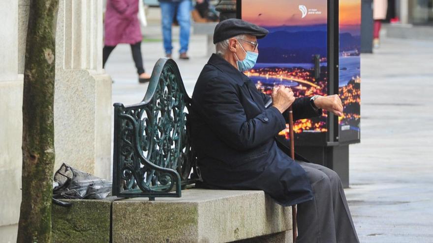 Un hombre mayor, con mascarilla, descansando en un banco en el centro de Vilagarcía.